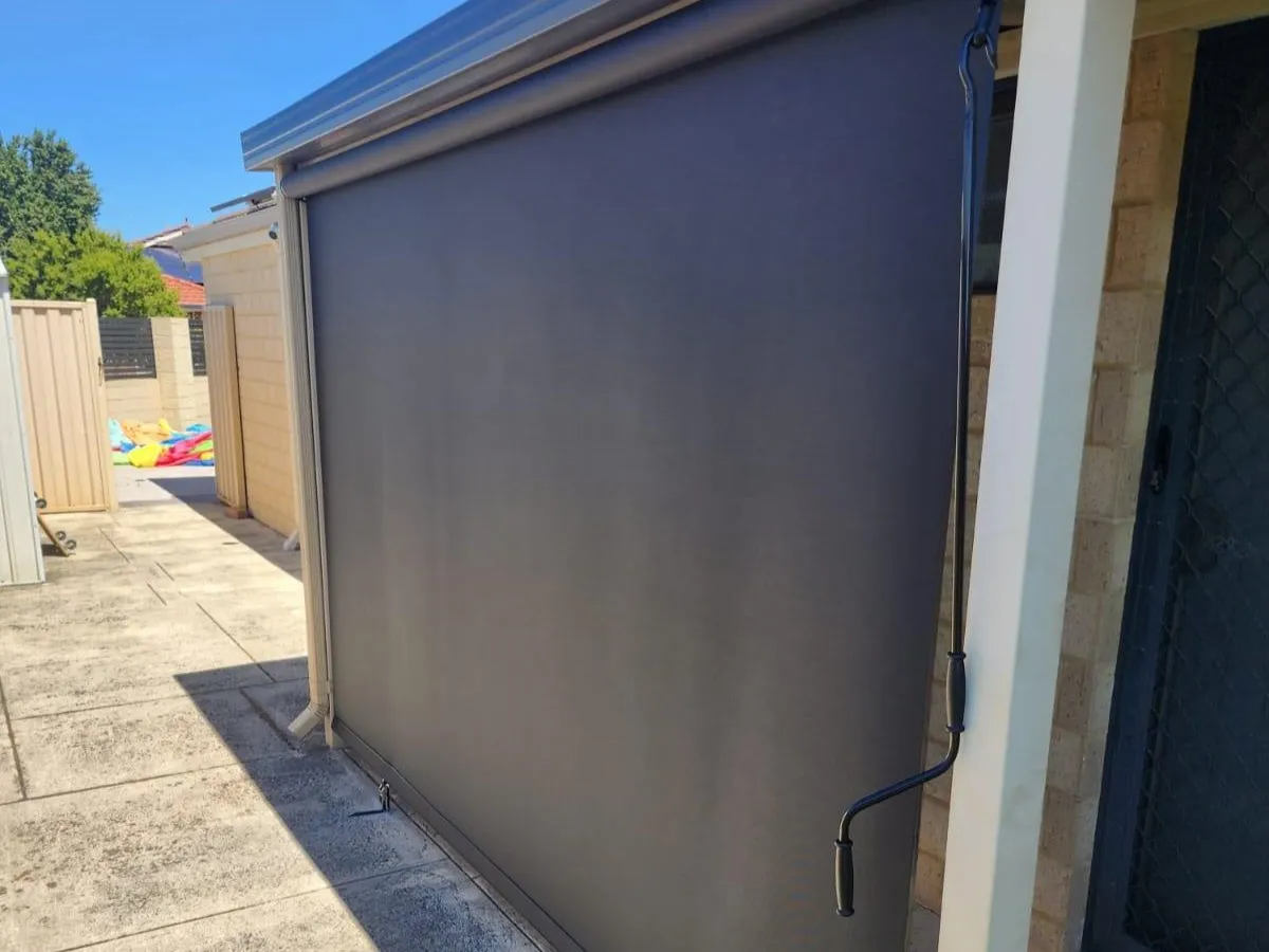 Charcoal roller shutter closed over a side window of a rendered home