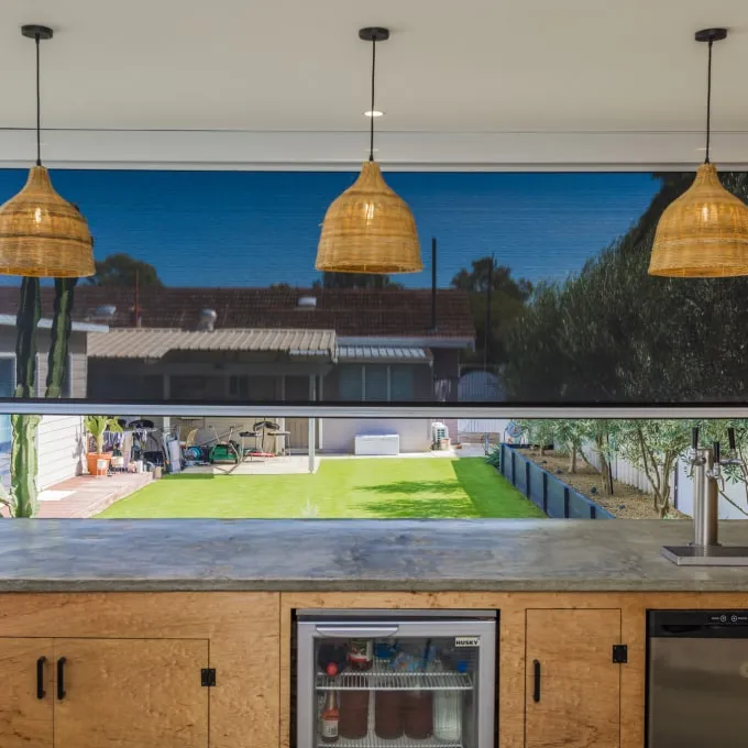 Outdoor blind framing the garden from an outdoor kitchen with pendant lights