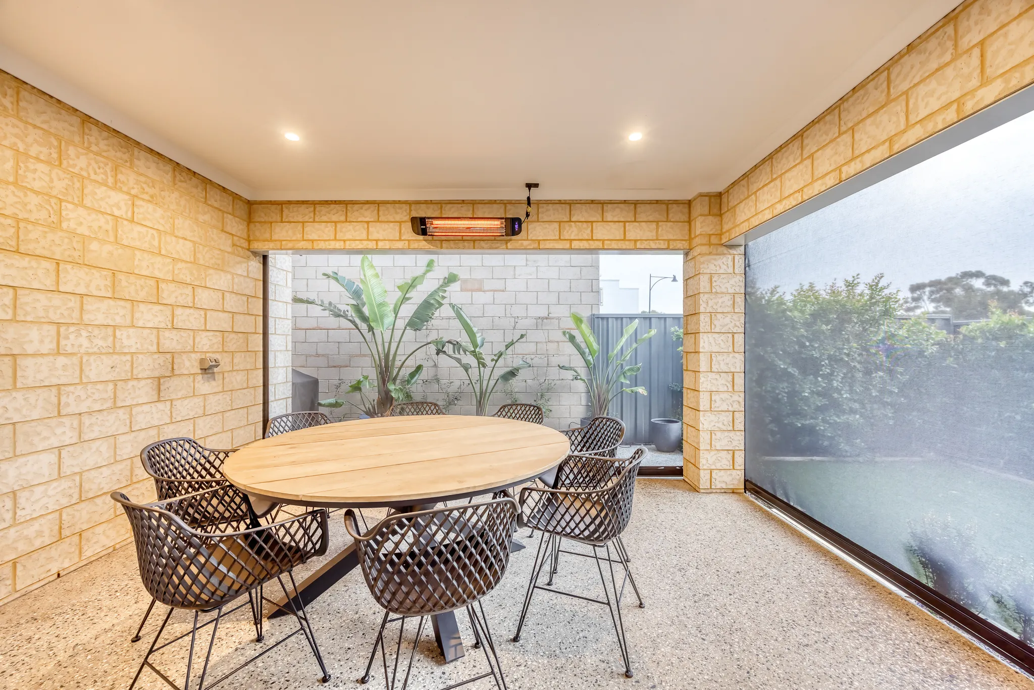Covered alfresco with a dining setting and a clear outdoor blind lowered