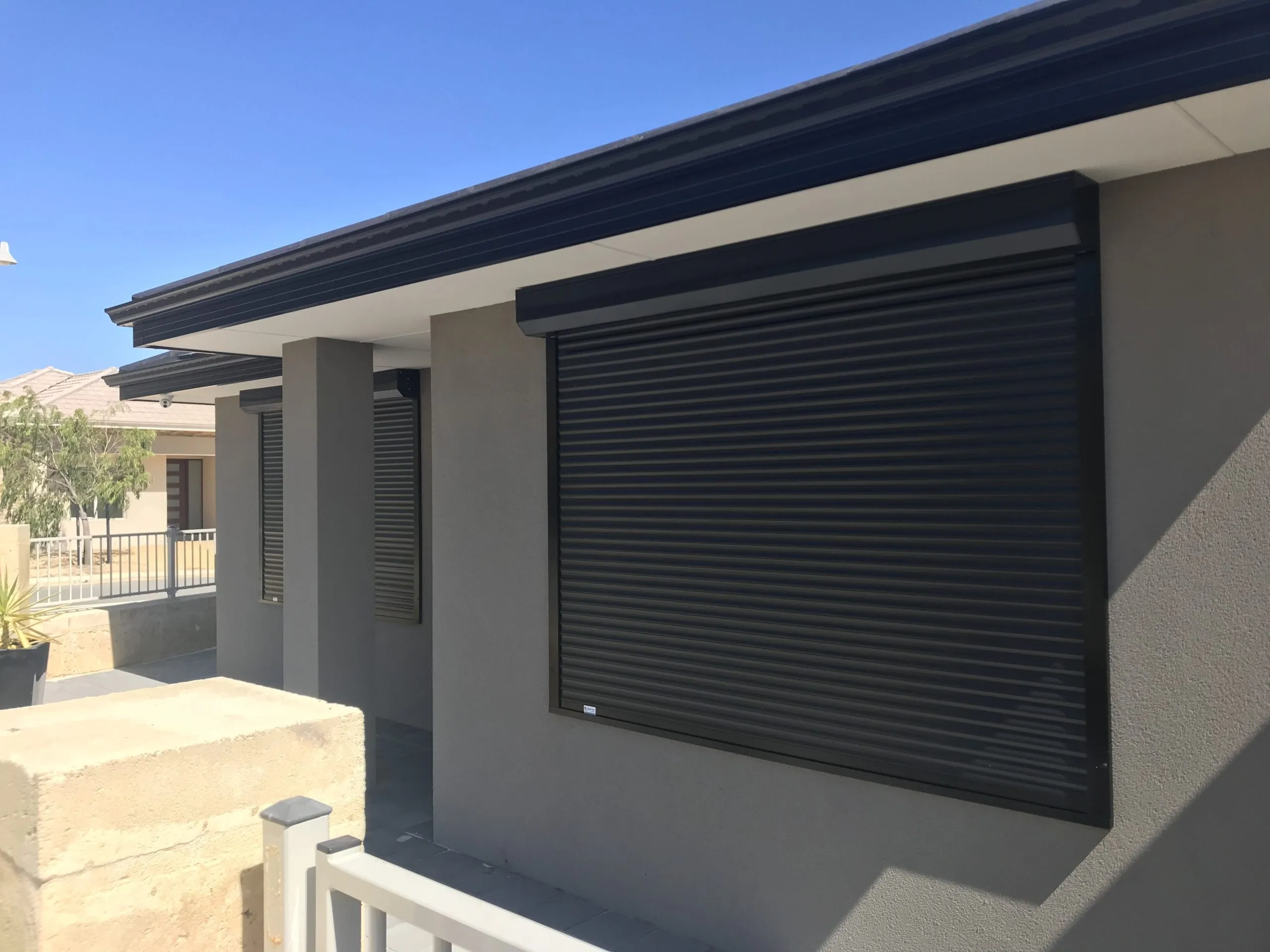 Black roller shutters closed over the front windows of a modern Perth home