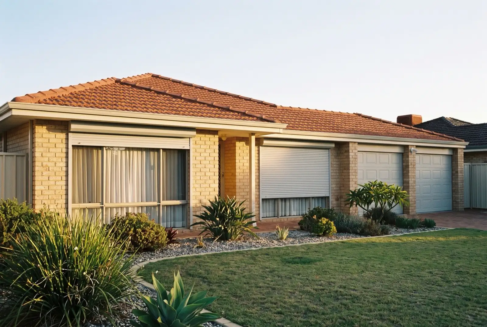 Illustration of pale grey roller shutters on a 1990s brick house