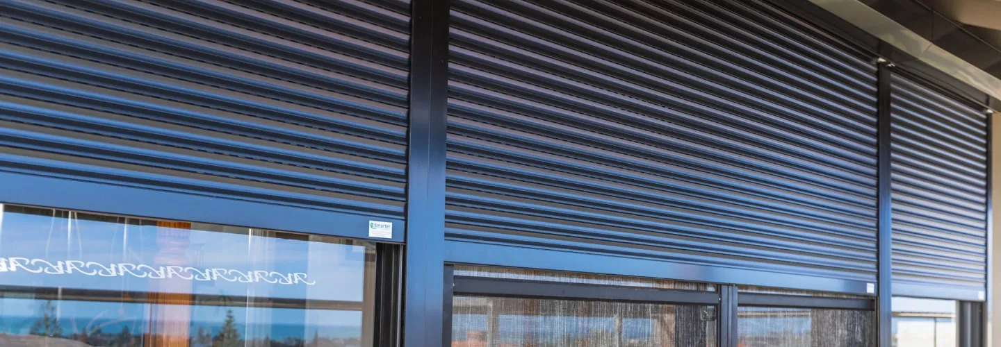 Dark roller shutters closed over a row of shopfront windows