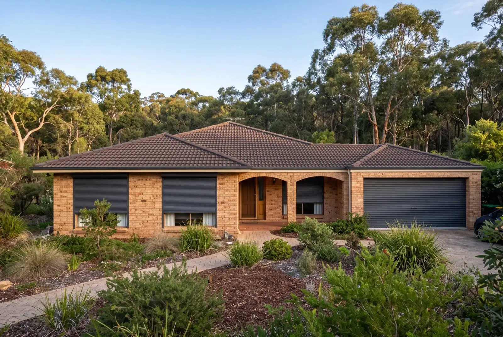 Illustration of charcoal roller shutters on a 1990s brick house on a bush block