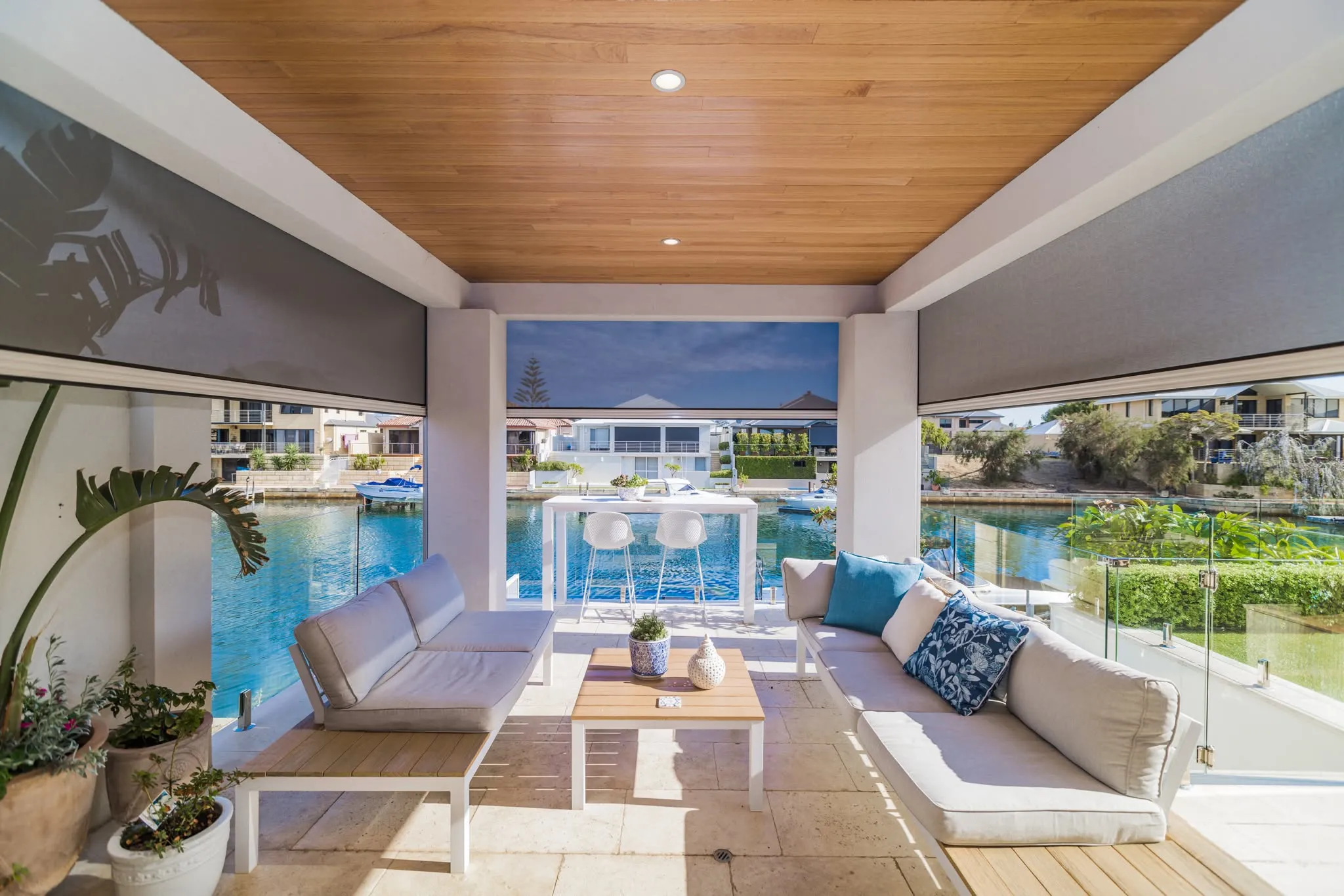 Grey Slidetrack outdoor blinds half-lowered on a canal-side alfresco with lounge seating