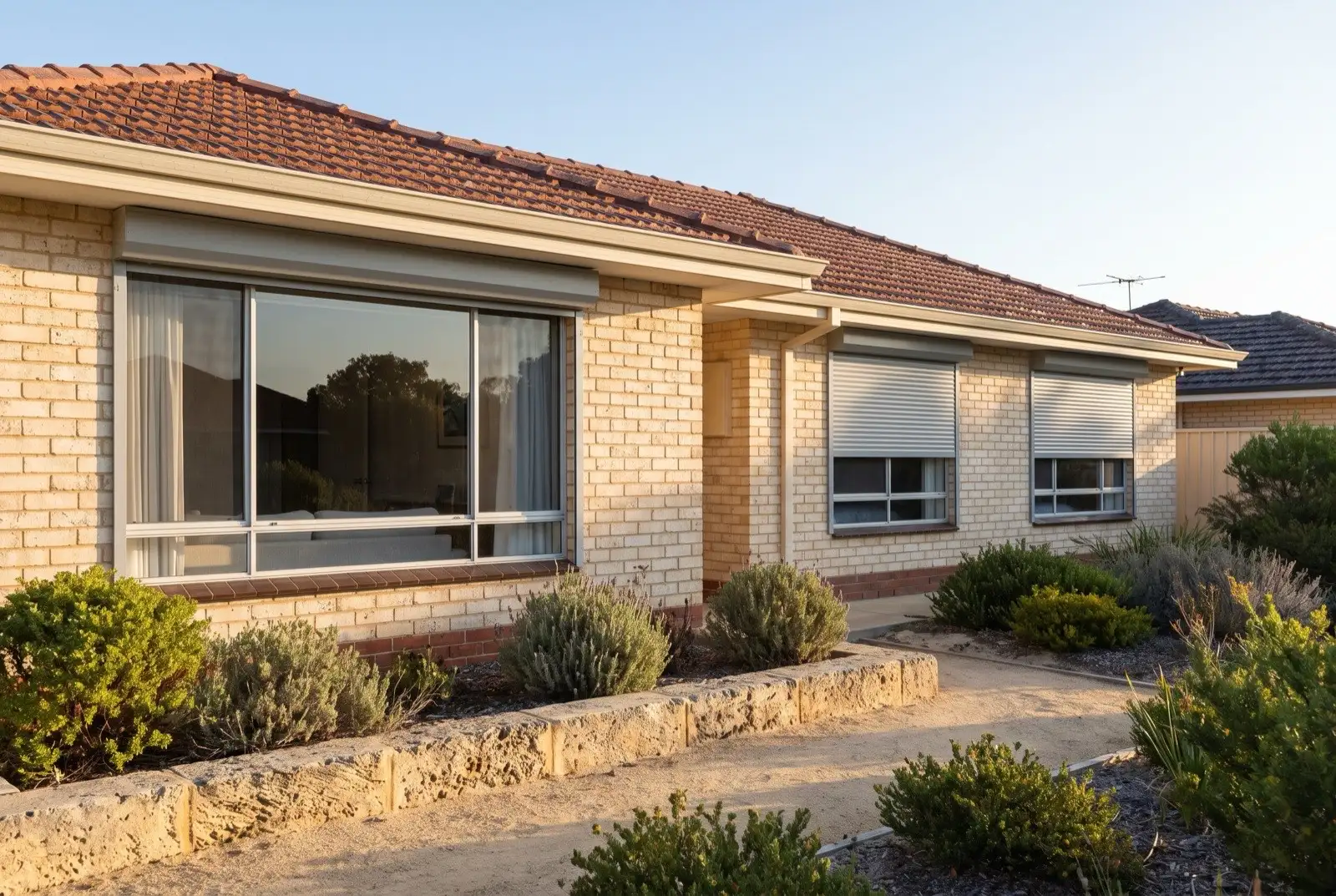 Illustration of mid grey roller shutters on a 1970s brick house near the coast