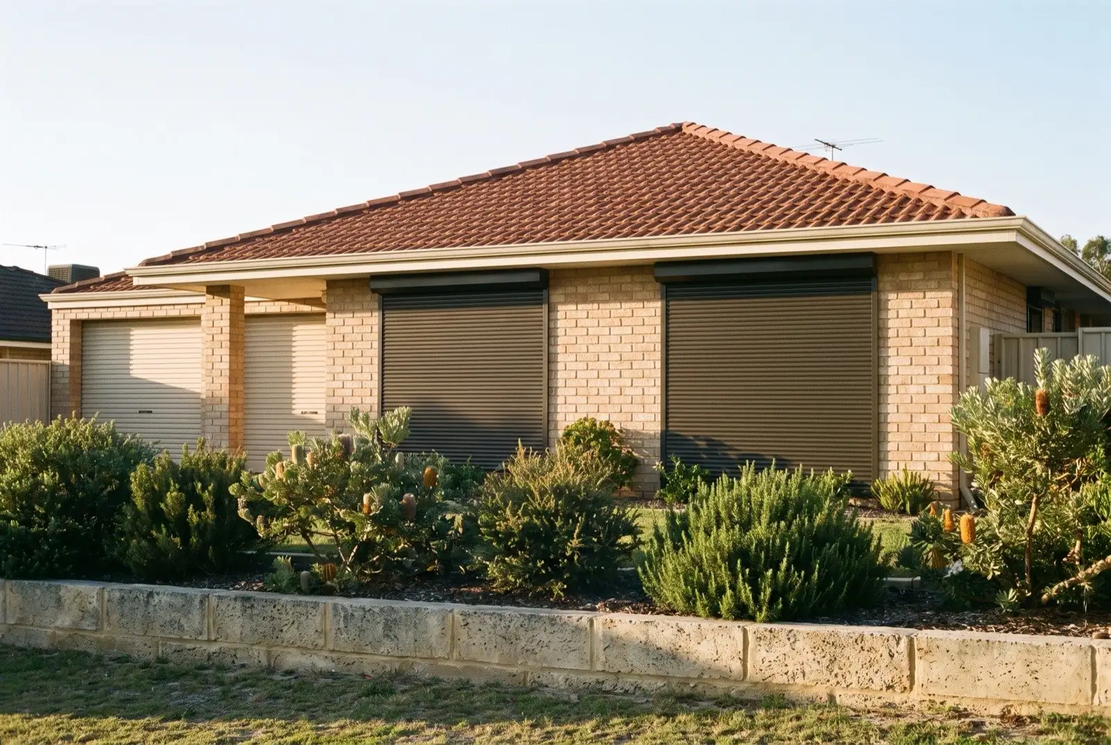 Illustration of dark bronze roller shutters on a 1990s brick house near the coast